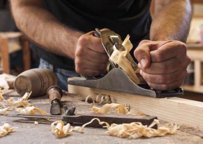 Carpenter,Working,With,Plane,On,Wooden,Background